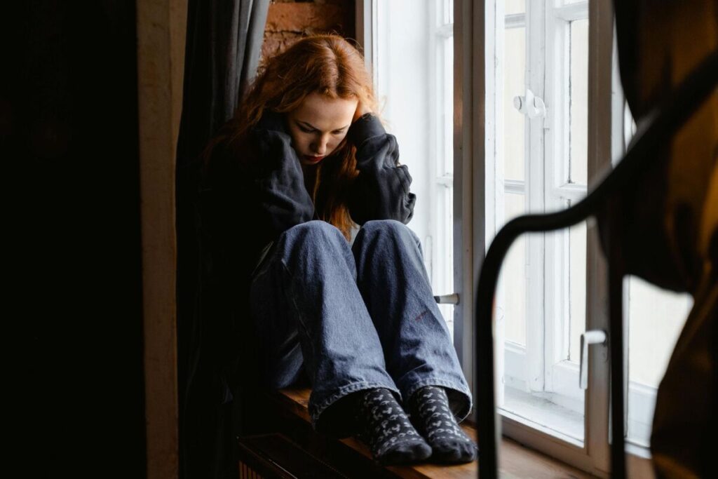 Sad woman sitting alone by a window