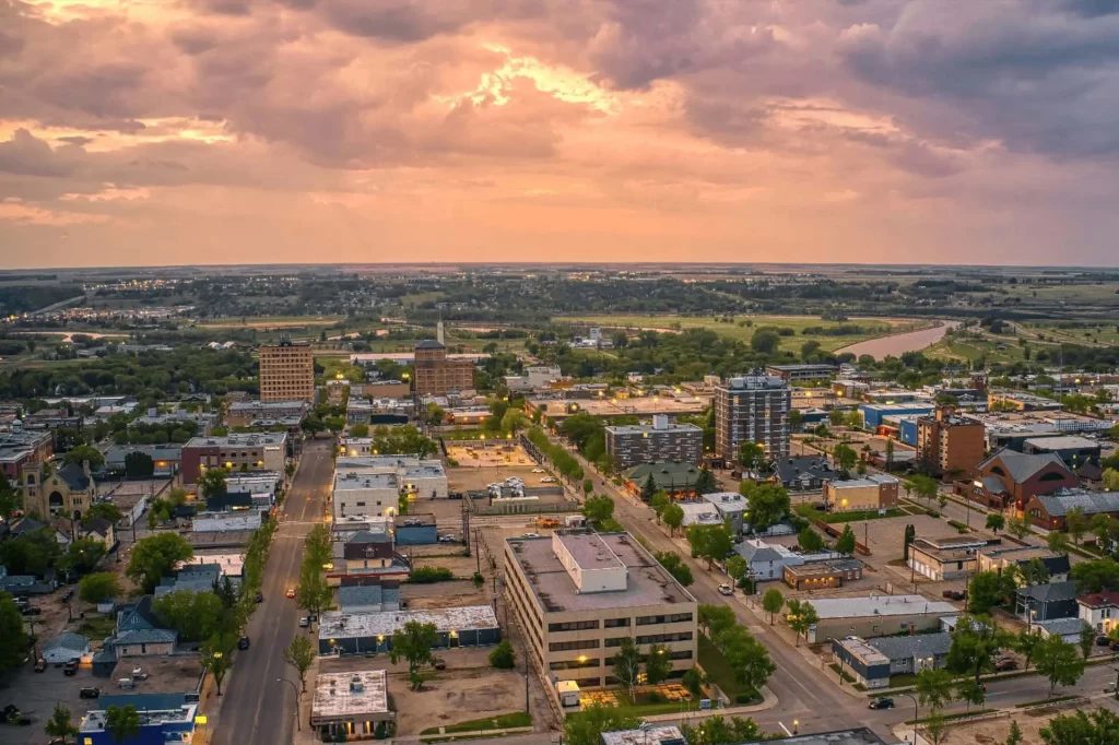 Eastern Manitoba 2 Aerial sunset view of Winkler in Southern Manitoba with homes, roads, and farmland beneath colorful clouds.